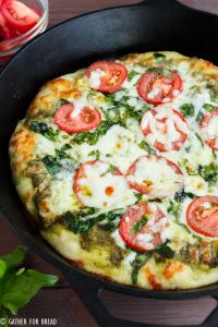 Skillet Pizza with Pesto Tomatoes and Spinach - Homemade pizza pie dough made in cast iron skillet with fresh pesto, tomato, and spinach toppings. Ready for Friday pizza night with these garden-fresh ingredients.