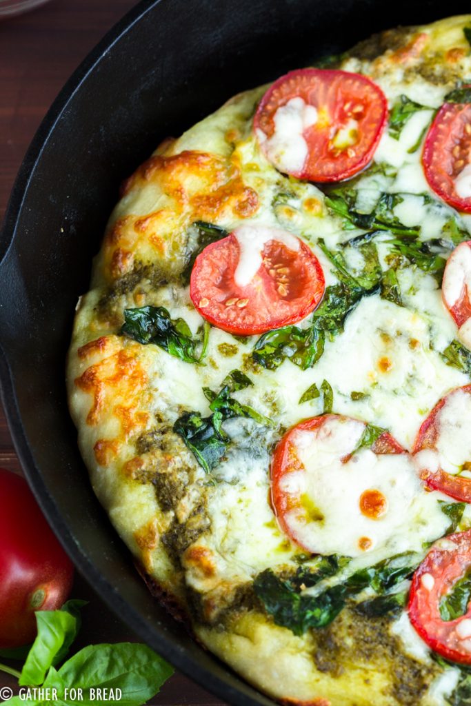 Skillet Pizza with Pesto Tomatoes and Spinach - Homemade pizza pie dough made in cast iron skillet with fresh pesto, tomato, and spinach toppings. Ready for Friday pizza night with these garden-fresh ingredients.